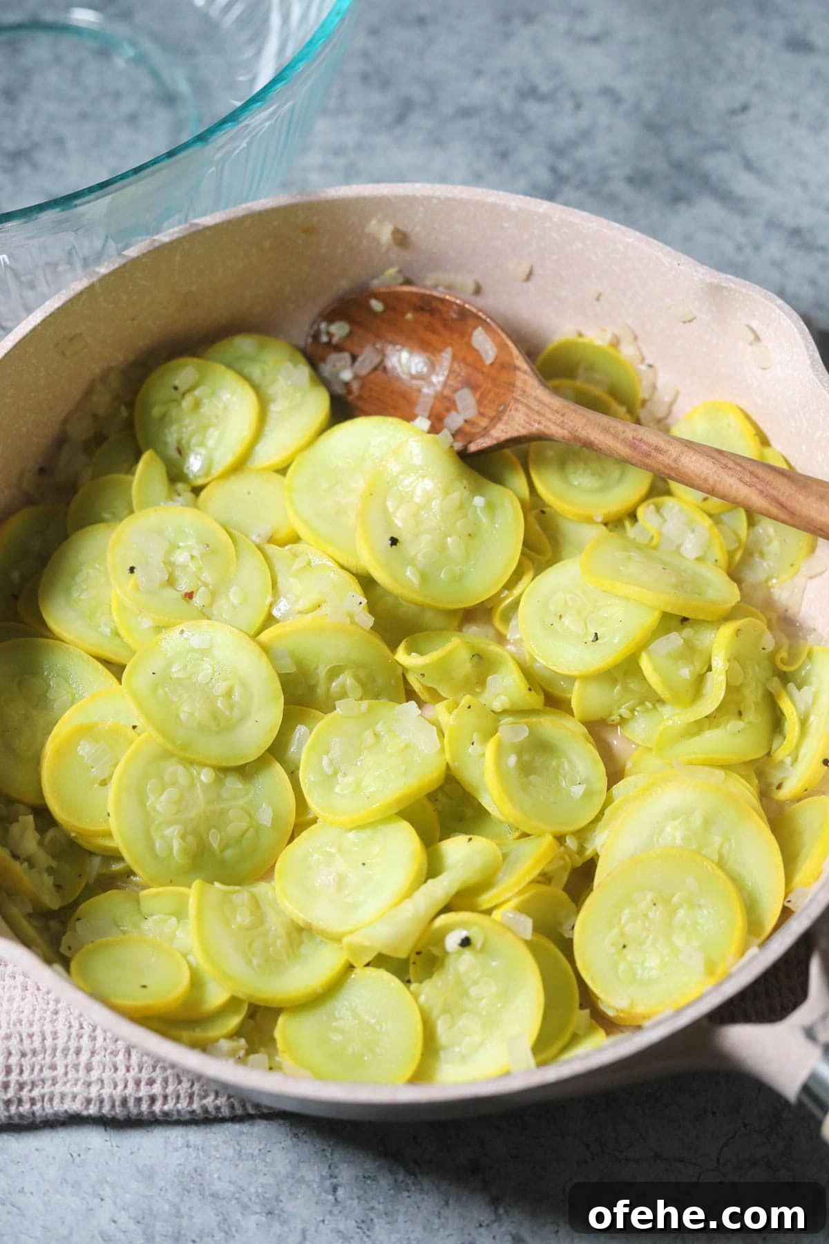 Southern Squash Casserole with Cheesy Cornbread Topping 4 Yellow squash and onion sautéing in a skillet.