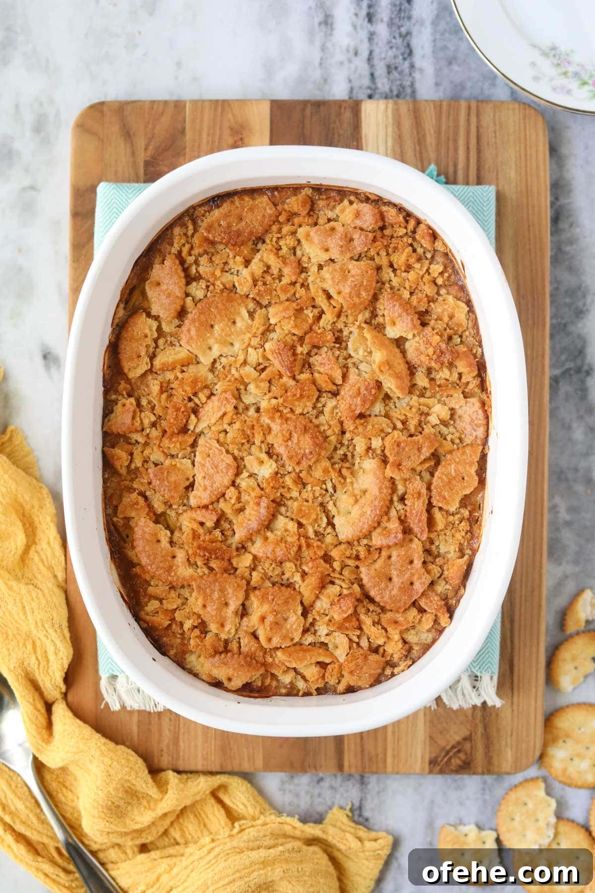Southern Squash Casserole with Cheesy Cornbread Topping 8 Southern squash casserole and a white baking dish sitting on top of a wooden cutting board.