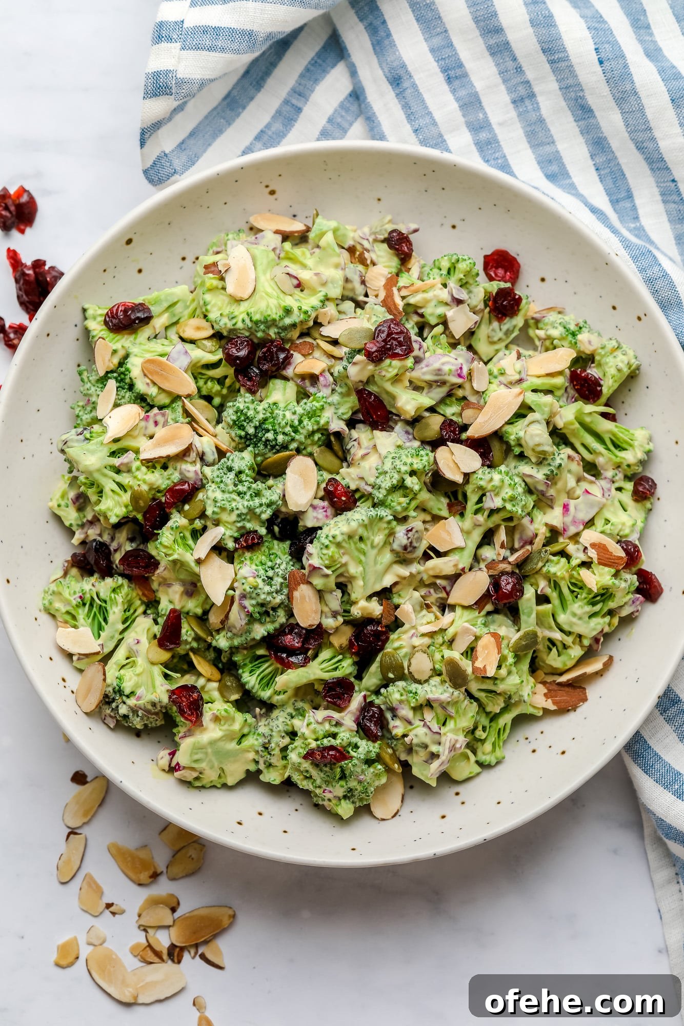 Vegan Broccoli Salad with Creamy Cashew Dressing 2 vegan broccoli salad tossed in creamy dressing and topped with almonds in a large white bowl.
