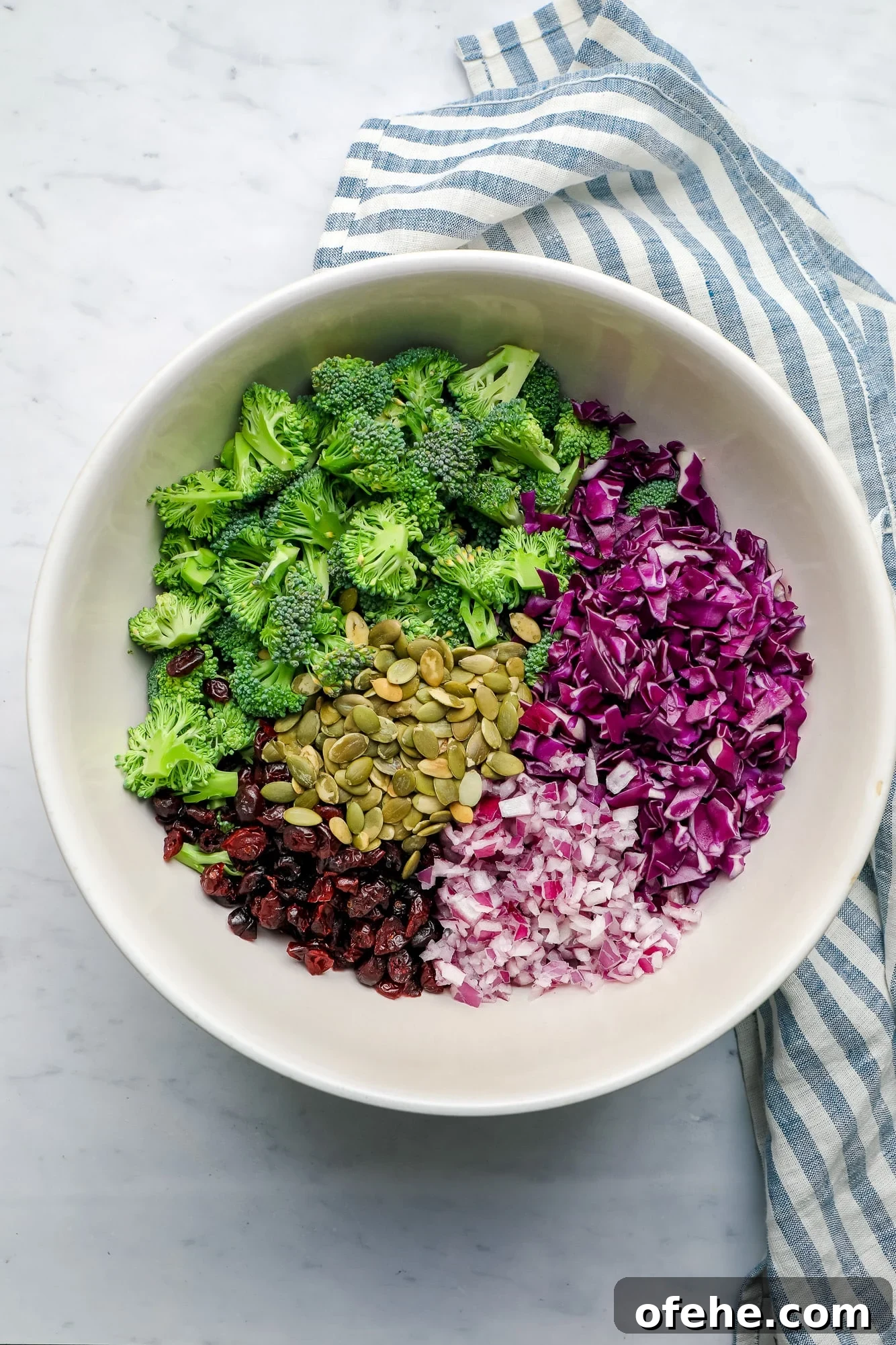 Vegan Broccoli Salad with Creamy Cashew Dressing 4 ingredients for vegan broccoli salad together in a large white bowl.