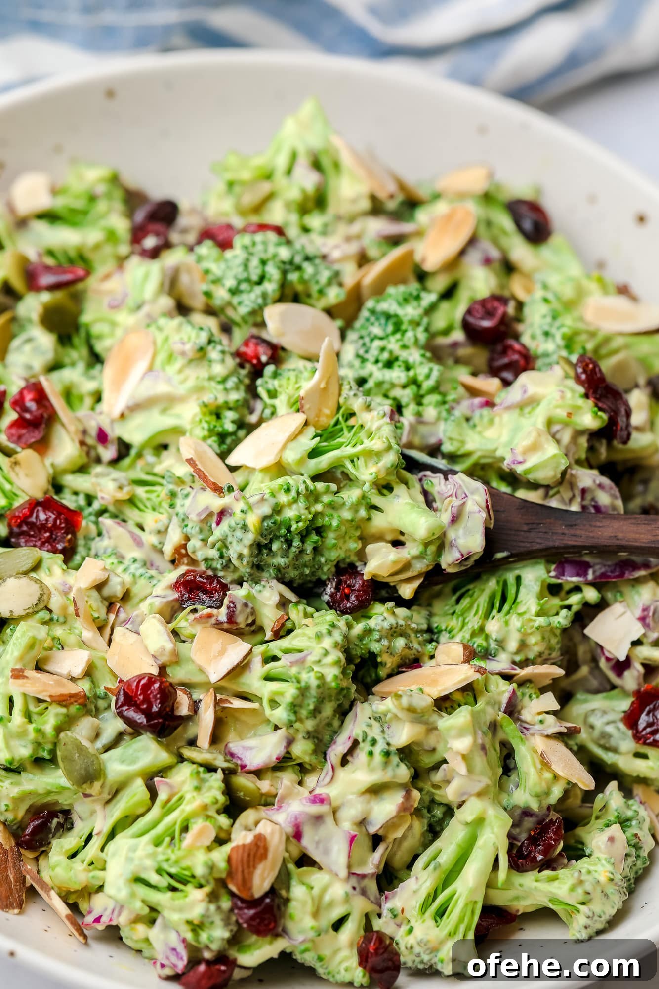 Vegan Broccoli Salad with Creamy Cashew Dressing 7 using a wood spoon to scoop up a bite of vegan broccoli salad.