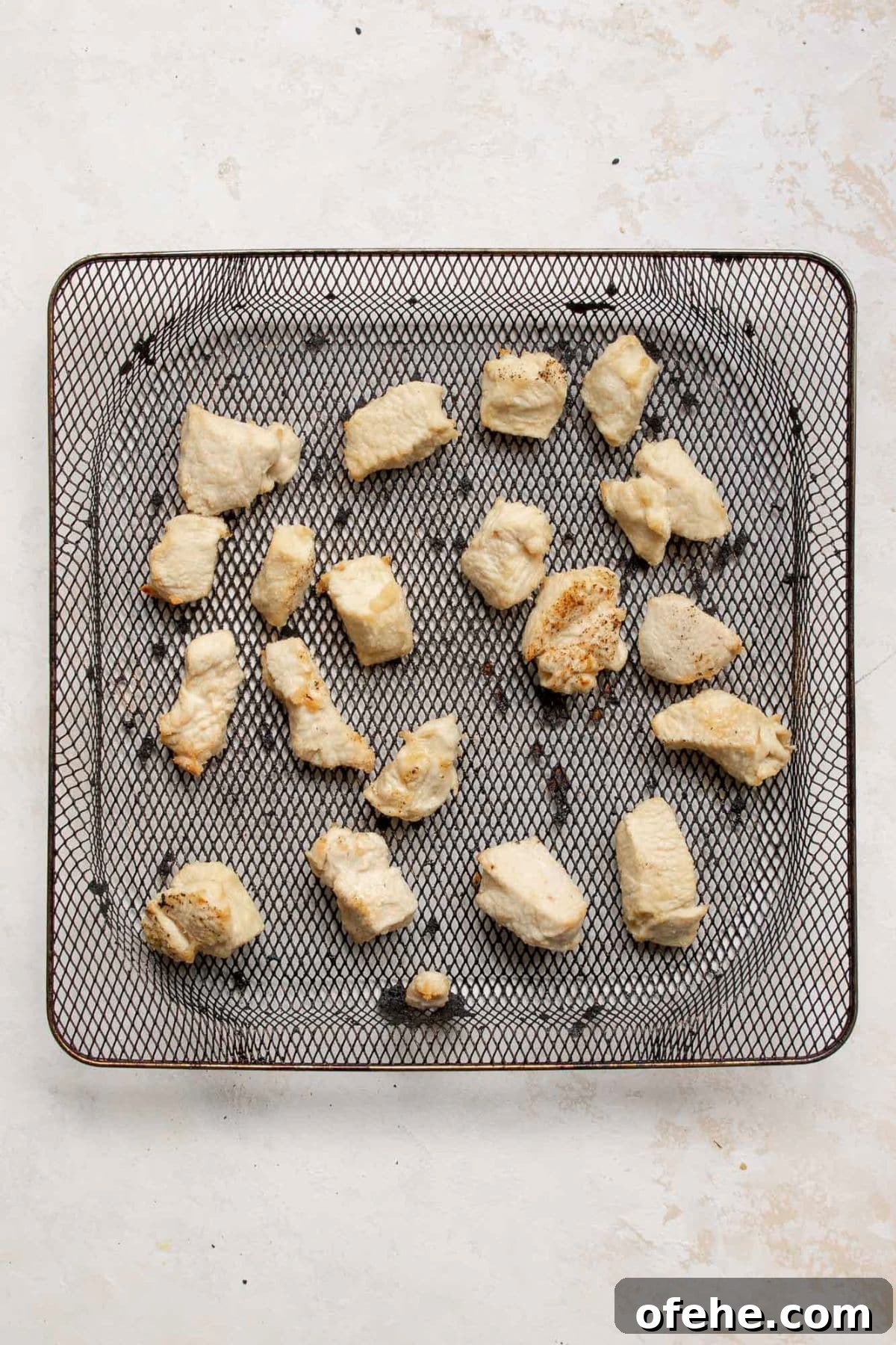 Crispy Sticky Air Fryer Teriyaki Chicken 7 Crispy golden chicken bites in an air fryer basket after cooking.