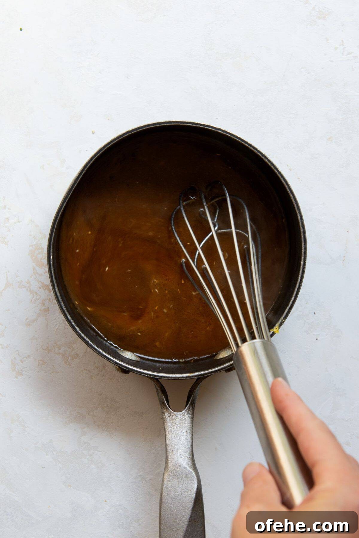 Crispy Sticky Air Fryer Teriyaki Chicken 8 Whisking homemade teriyaki sauce in a saucepan made with soy sauce, honey, and orange juice.