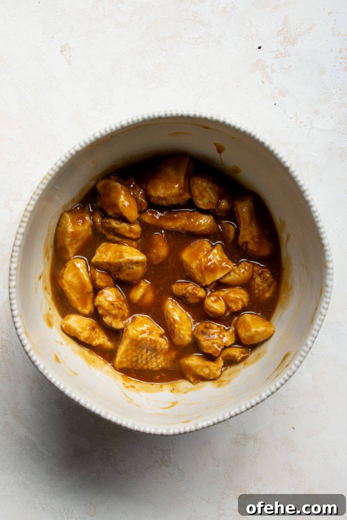 Crispy Sticky Air Fryer Teriyaki Chicken 9 Crispy chicken pieces tossed in homemade teriyaki sauce in a mixing bowl.