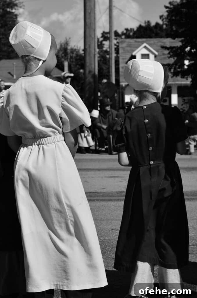 Amish girls and people standing around watching something.
