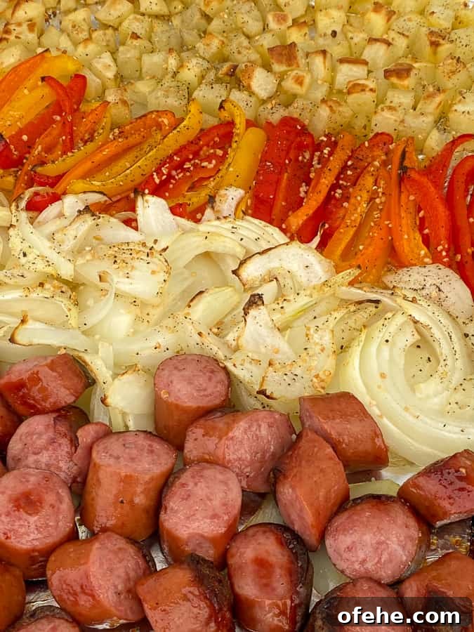 Close up Kielbasa with onions, peppers and potatoes on a sheet pan