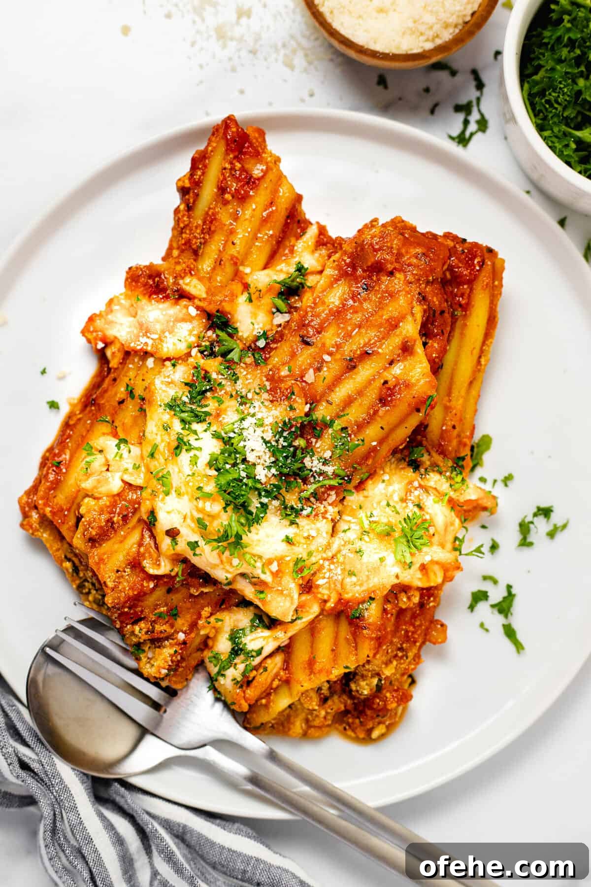 Creamy Spinach and Cheese Manicotti (Vegetarian Recipe) 2 White plate with three homemade manicotti topped with Parmesan and parsley