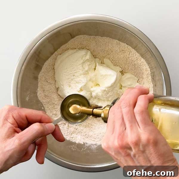 Adding olive oil to the dough ingredients.
