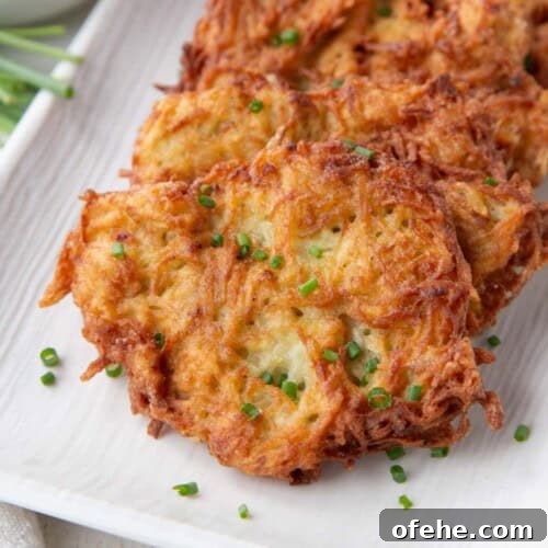 crispy potato pancakes topped with chopped chives on a white platter.