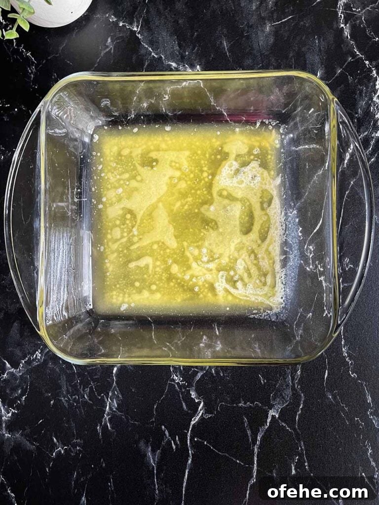 Melted butter in a square glass baking dish.