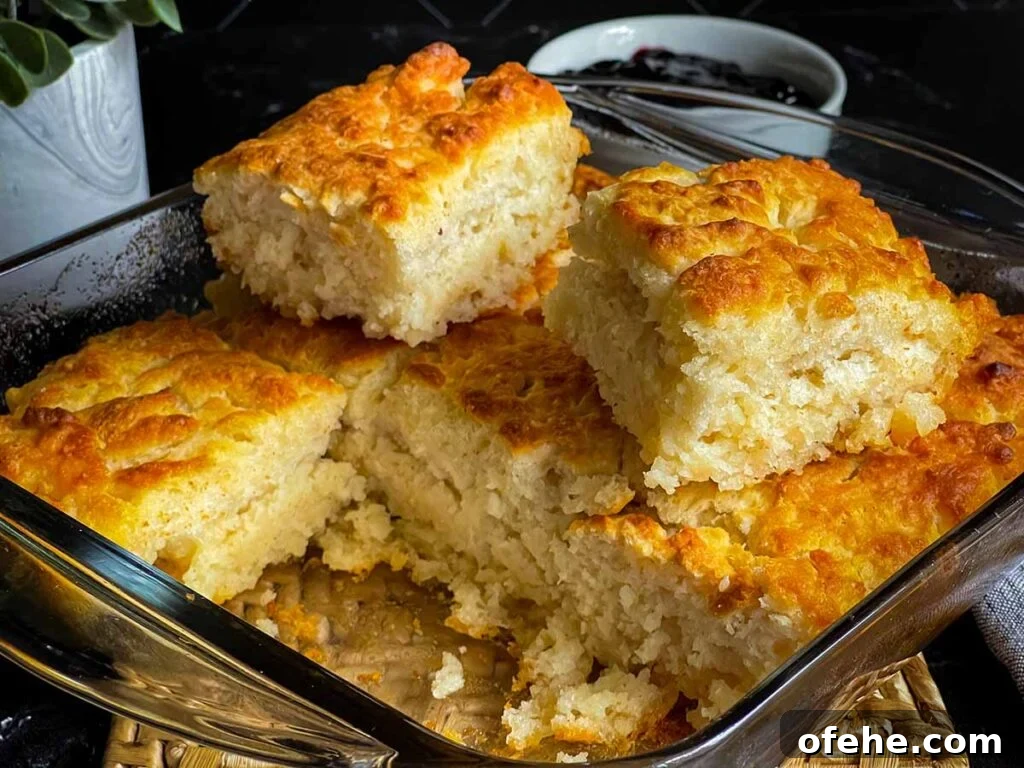 Two butter swim biscuits sitting on top of the pan of biscuits cut into squares.