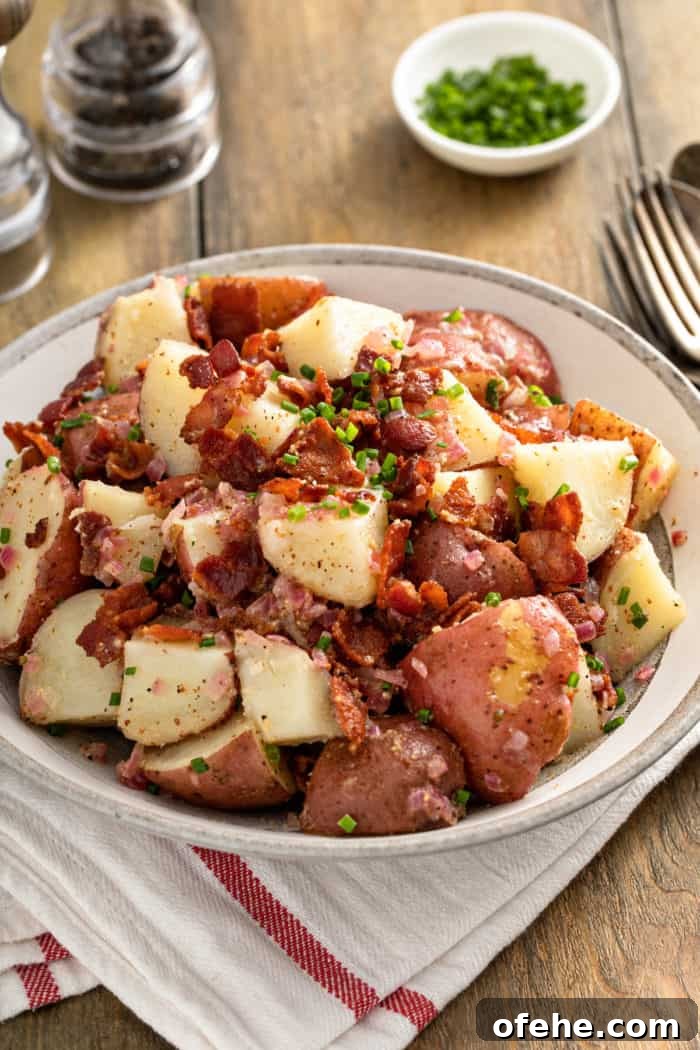 German potato salad, garnished with bacon and chives, in a large serving bowl.