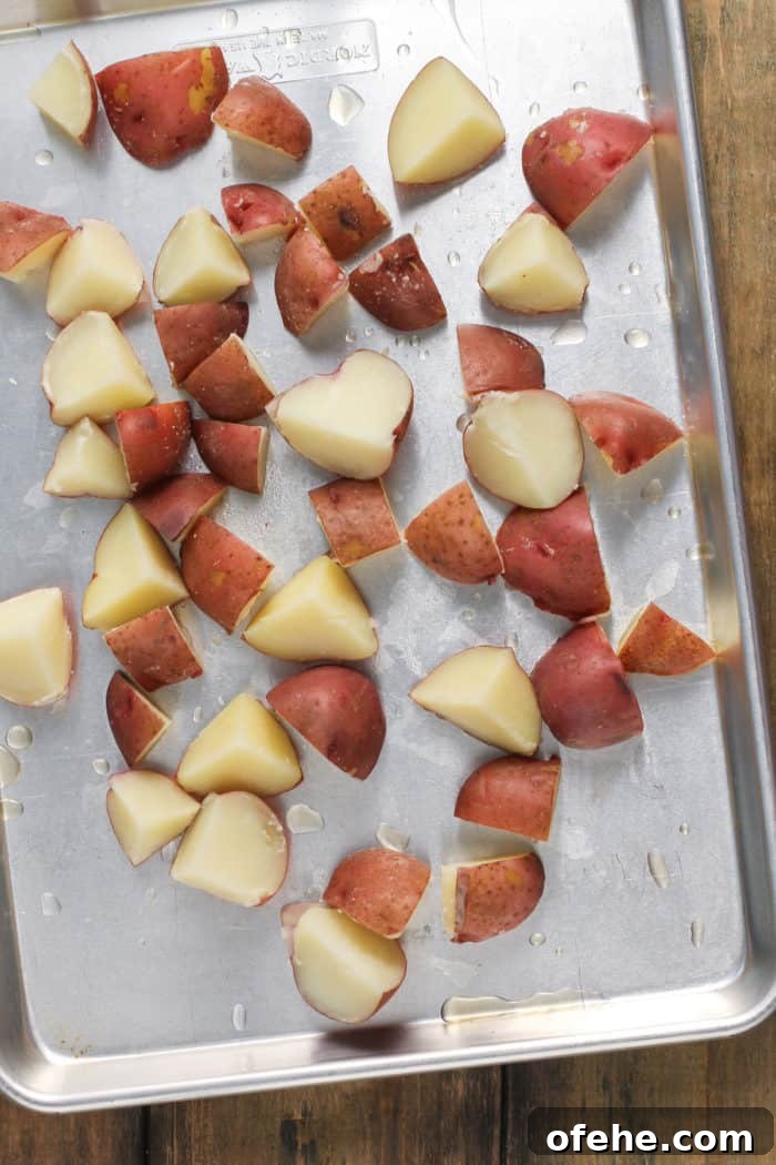 Cooked red potatoes spread out onto a metal sheet pan.