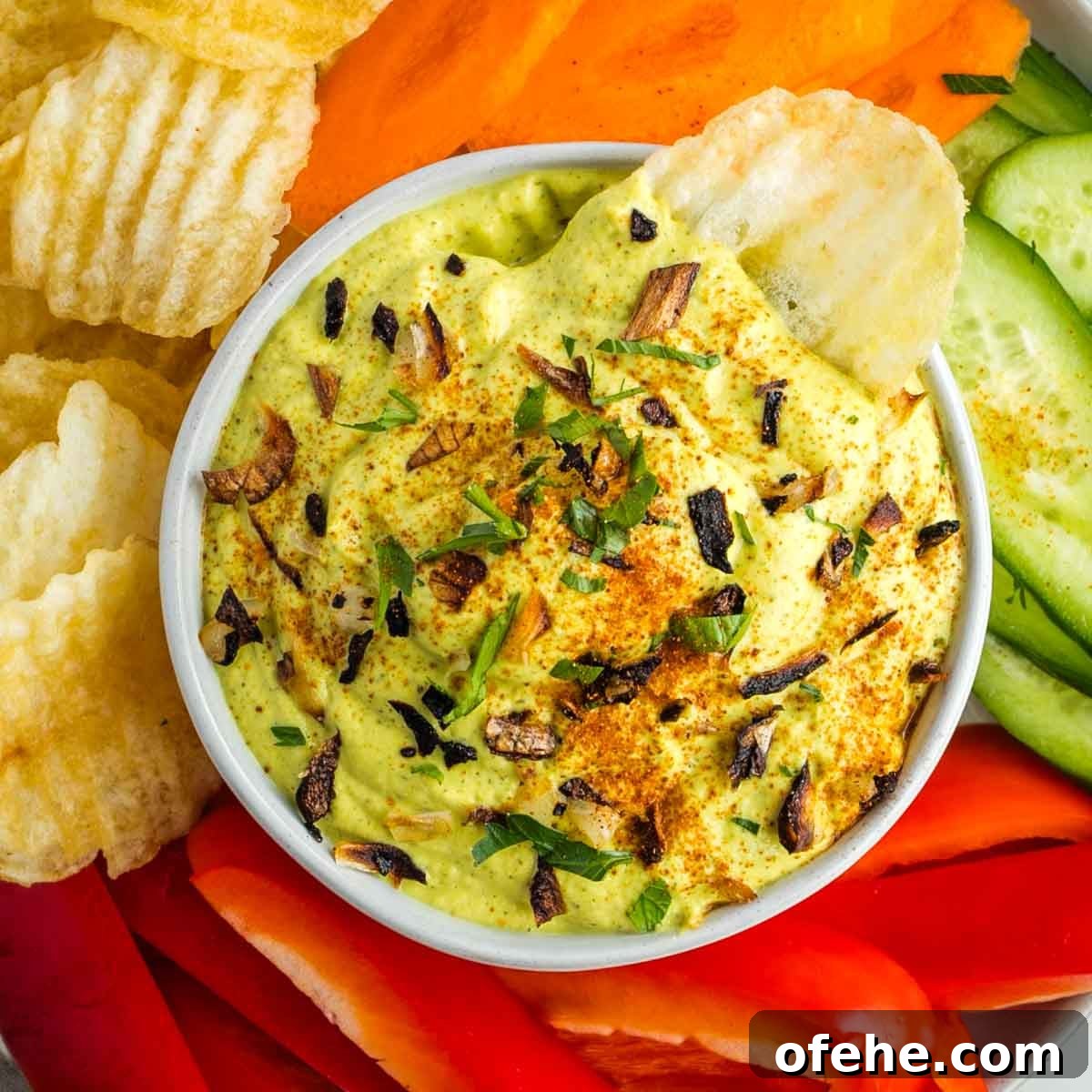 Wholesome Thanksgiving Recipes 2025 for a Lighter Feast 10 Zucchini and onion dip sprinkled with crispy onions, parsley and paprika. Surrounded by colorful veggies and chips.