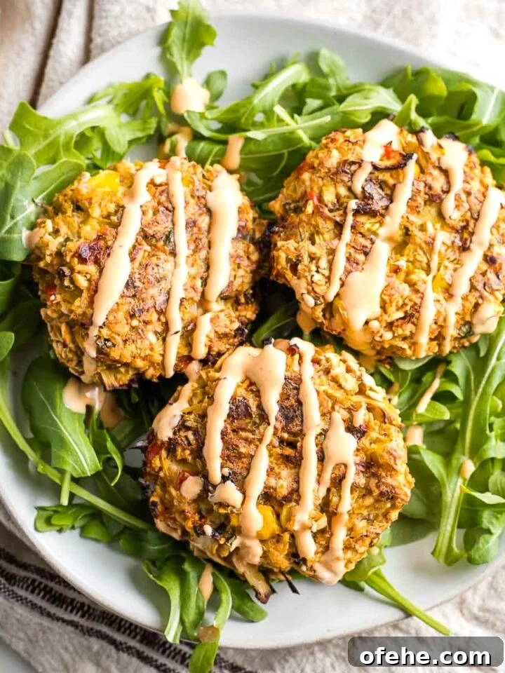 Three vegan crab cakes set atop arugula and drizzled with sriracha tahini.