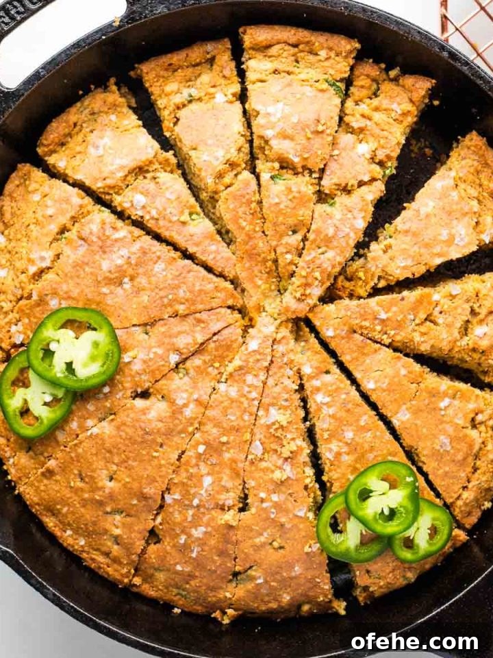 Corn bread with jalapenos cut into pie slices inside a cast iron skillet.