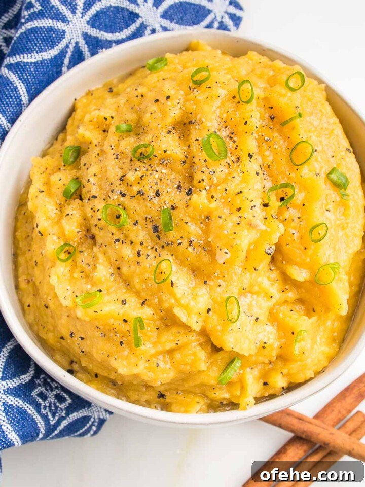 White bowl of mashed acorn squash, garnished with thinly sliced scallions.