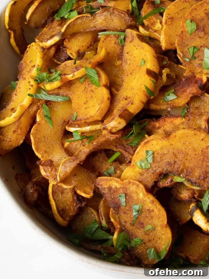 Bowl full of half moon shaped orange delicata squash with fresh green parsley sprinkled on top