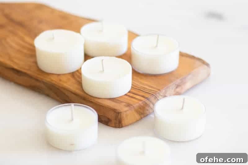 DIY Citronella Candles to Keep Mosquitoes Away 2 white tea light bug repellent candles on wooden cutting board.