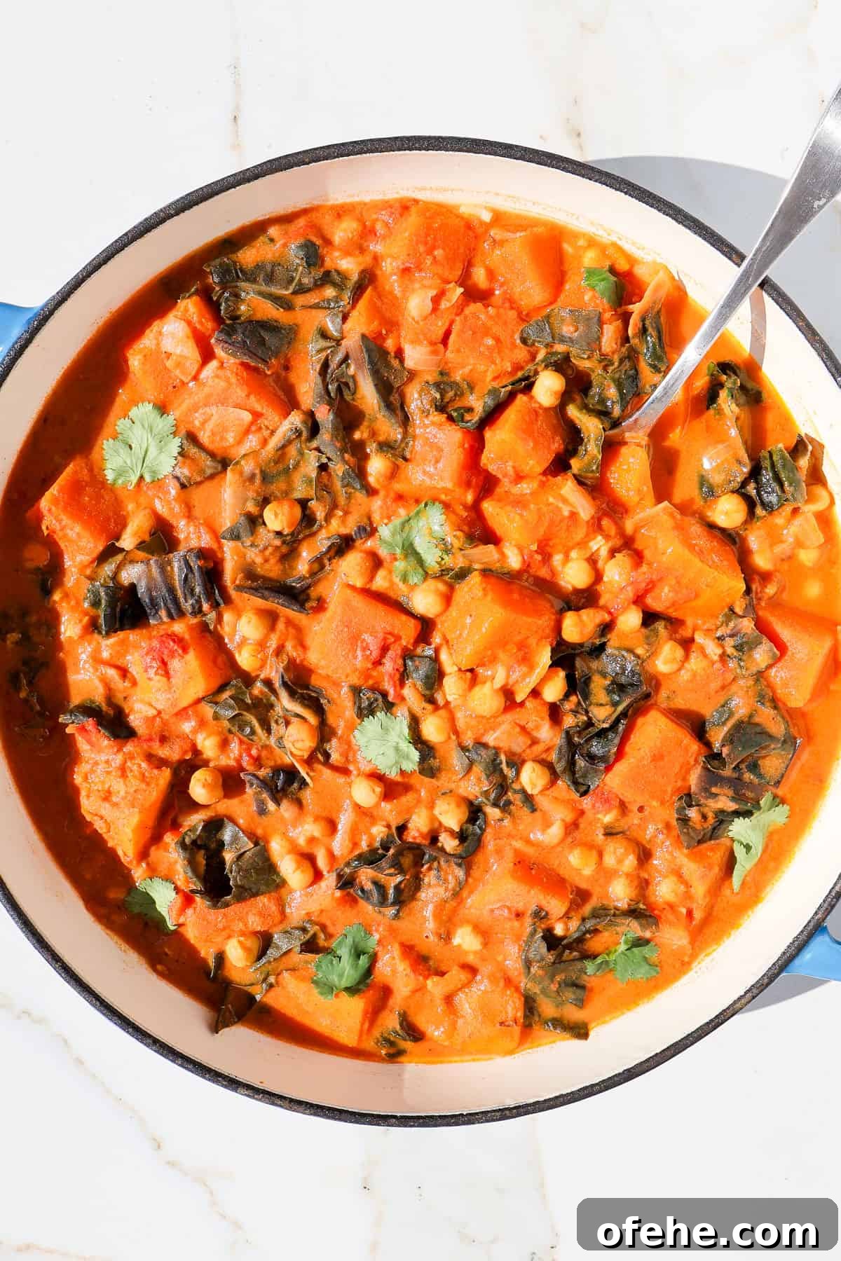 Butternut squash curry in a pot with a spoon.